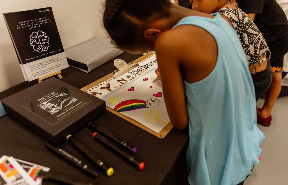 A child creating colourful artwork during an Aduma Adan workshop